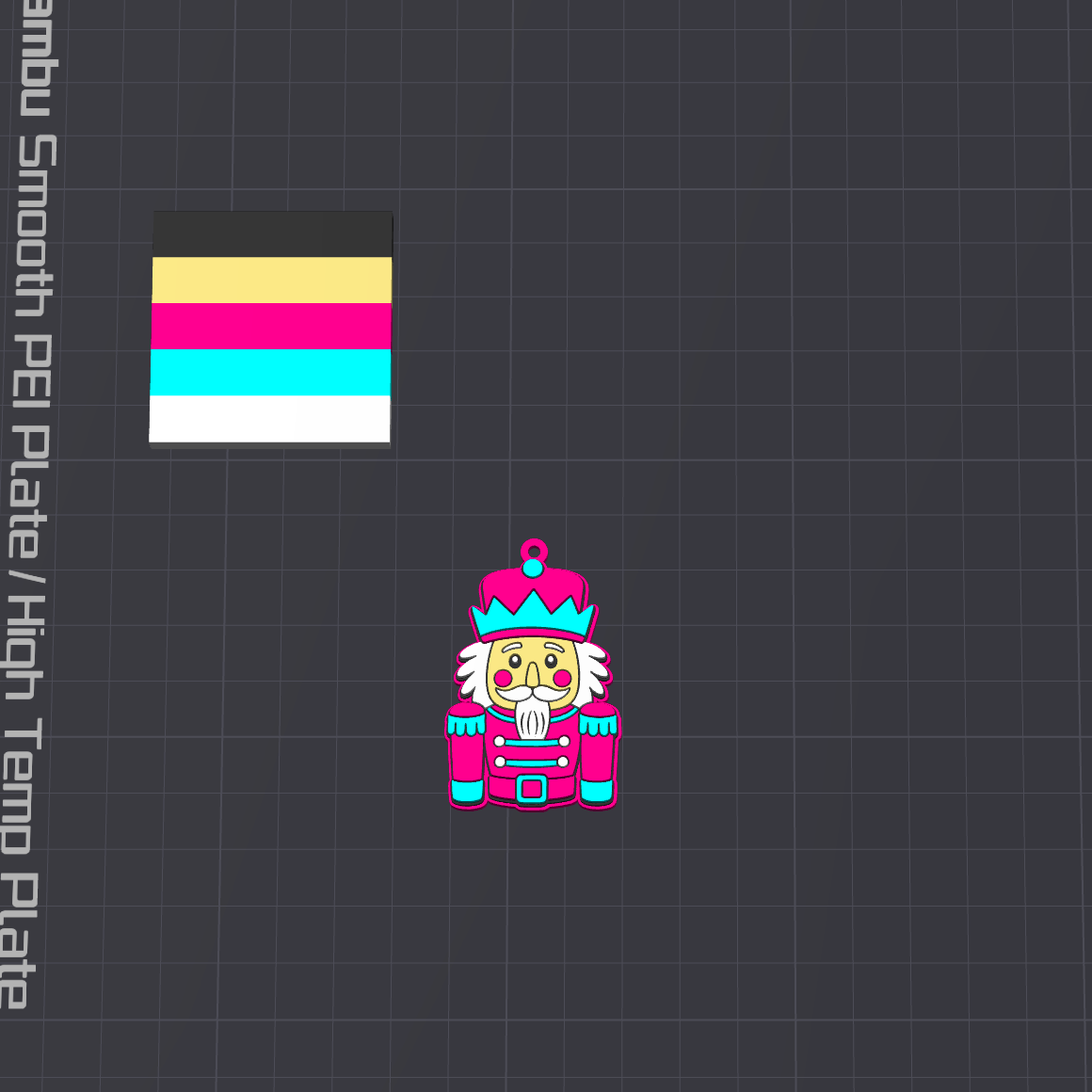A dark gray grid plate with a vertical text label reading 'Anodized Smooth PEI Plate / High Temp Plate' on the left side. On the plate, there is a small colorful illustrated nutcracker character and a small rectangular color sample showing black, beige, yellow, pink, magenta, cyan, and white stripes.