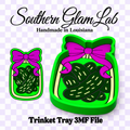 Digital design preview for a Southern Glam Lab handcrafted in Louisiana trinket tray 3D file. The design features a bright green tray filled with dark green pickles and topped with a magenta-purple ribbon bow, shown in both a close-up and a larger perspective view on a light purple checkered background.